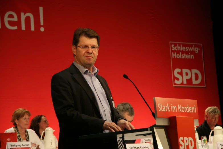 a man standing in front of a podium with people behind him