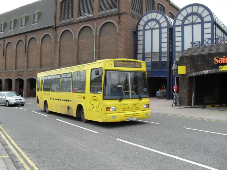 a yellow bus driving down a street near tall buildings