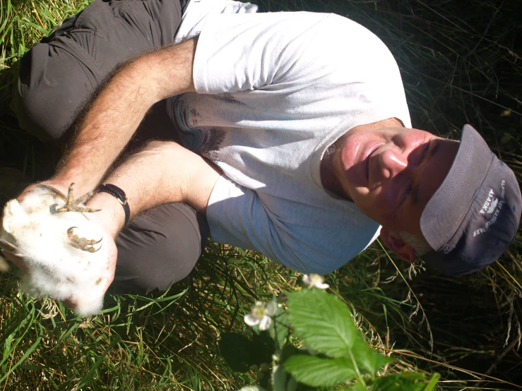 the man is crouching in a field holding a cat