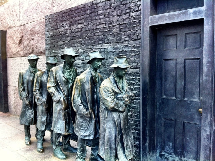 a row of bronze statues with people standing next to each other