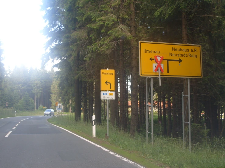 a couple of signs next to a road in the forest