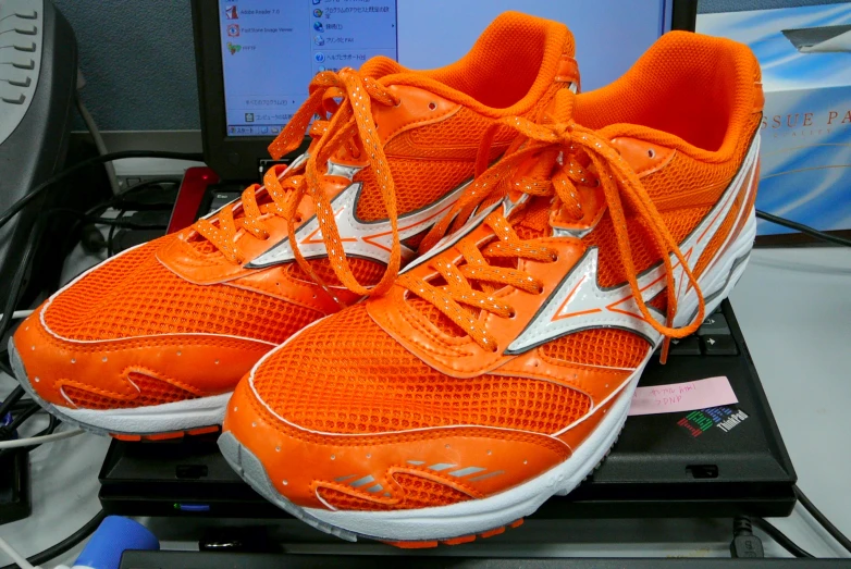 the bright orange shoe on top of the computer desk