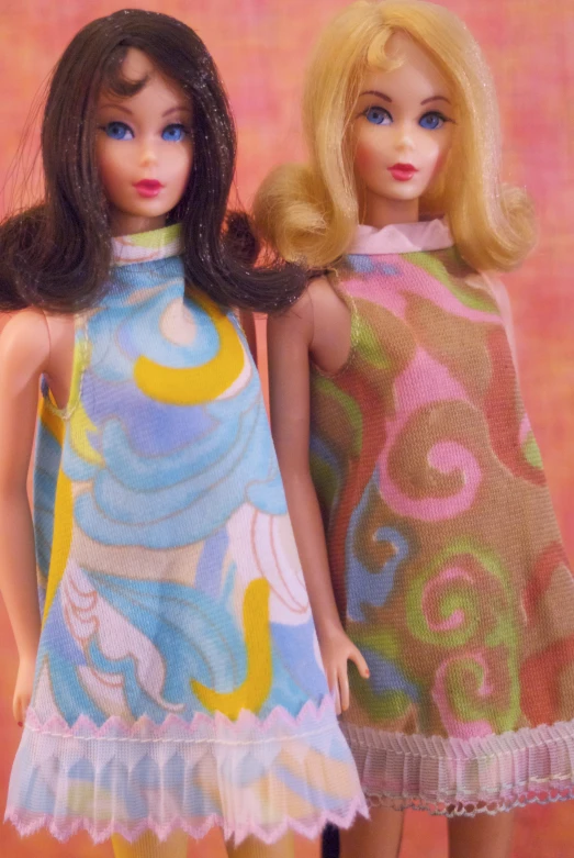 a couple of barbie dolls are standing next to each other