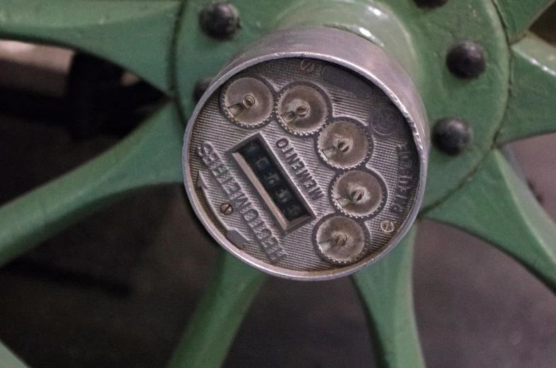 an old antique clock mounted to a green wheel