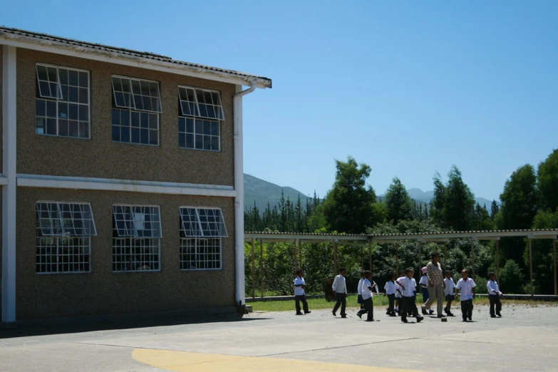 a group of people standing outside a building with some trees