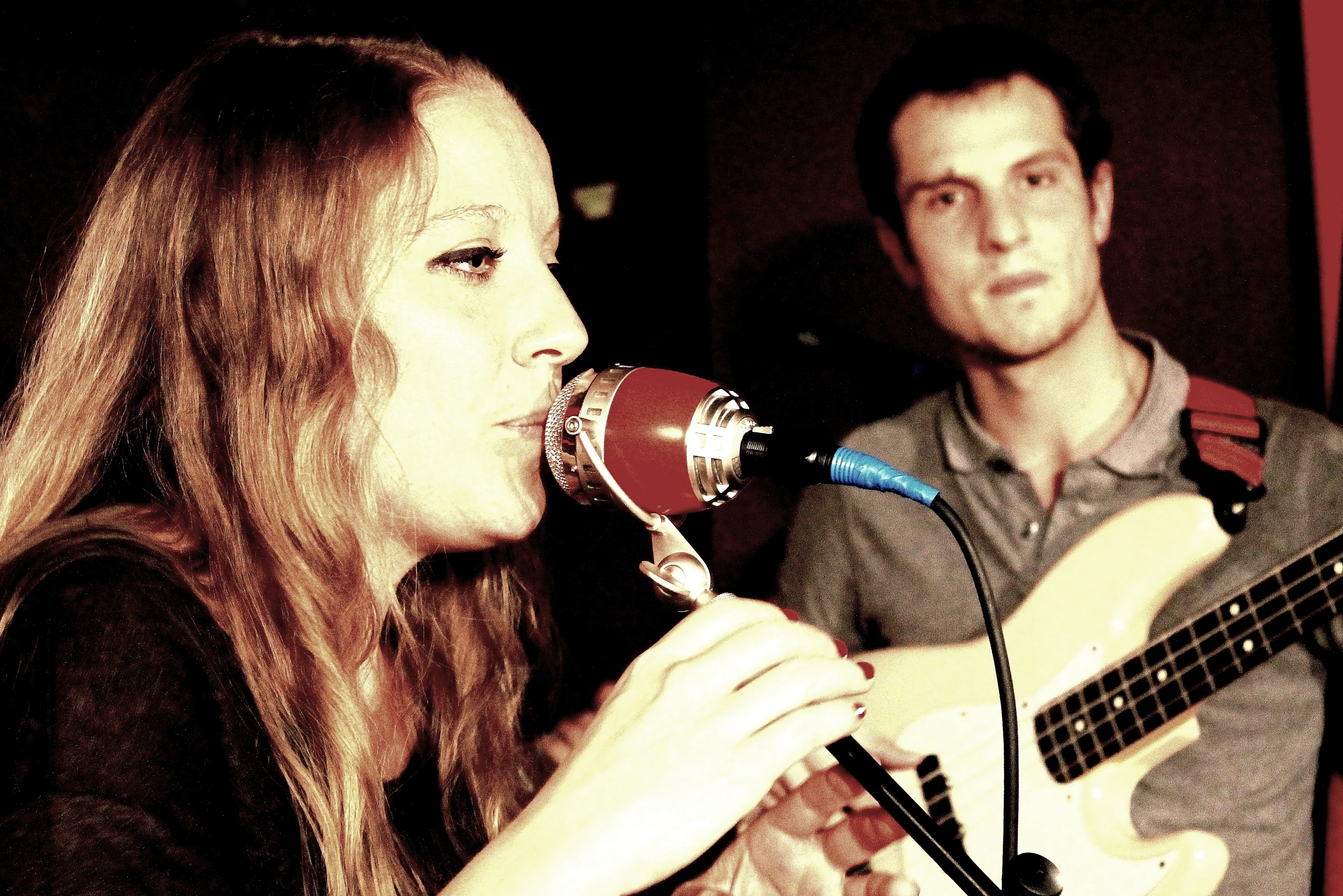 a man and woman singing into a microphone while holding a guitar