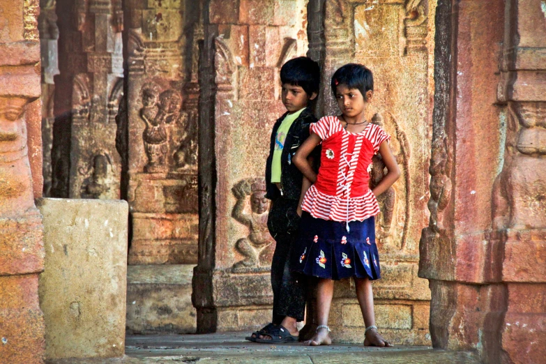 two boys standing outside in front of ancient carvings