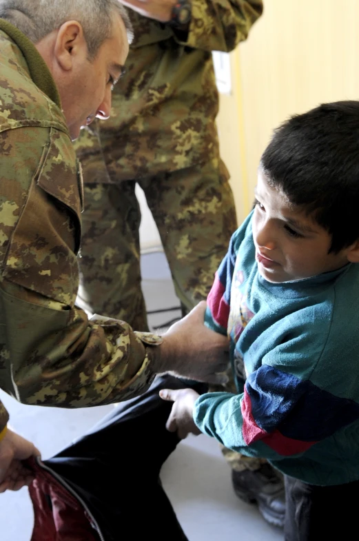 two men in military uniforms hold a boy up to him