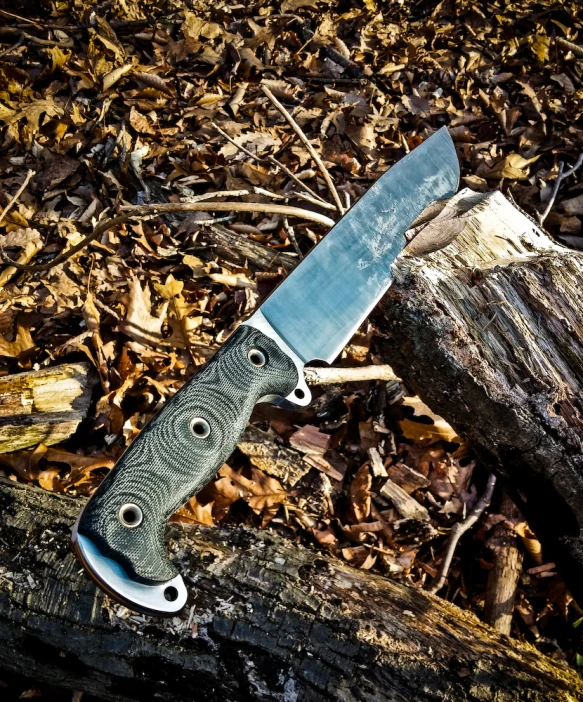 a big knife sitting on top of a piece of wood