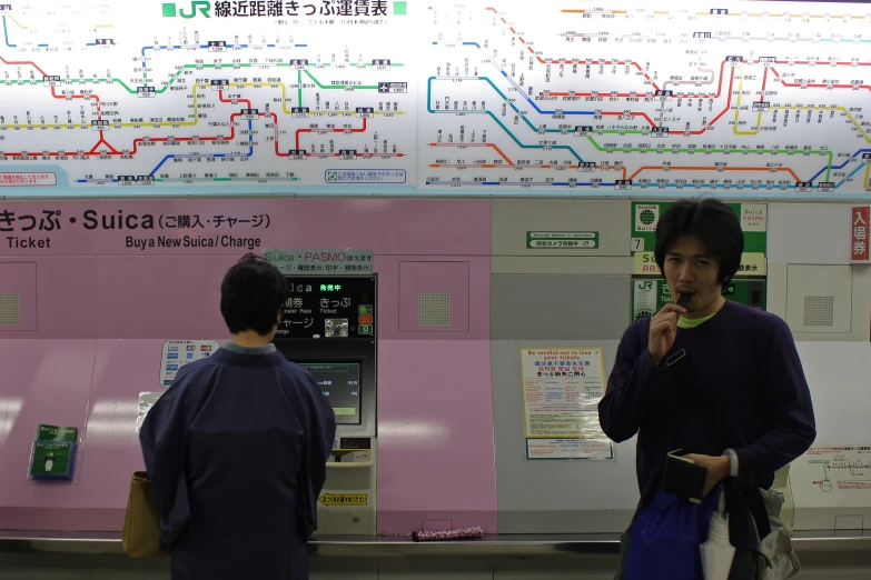 two men talking in front of a pay phone