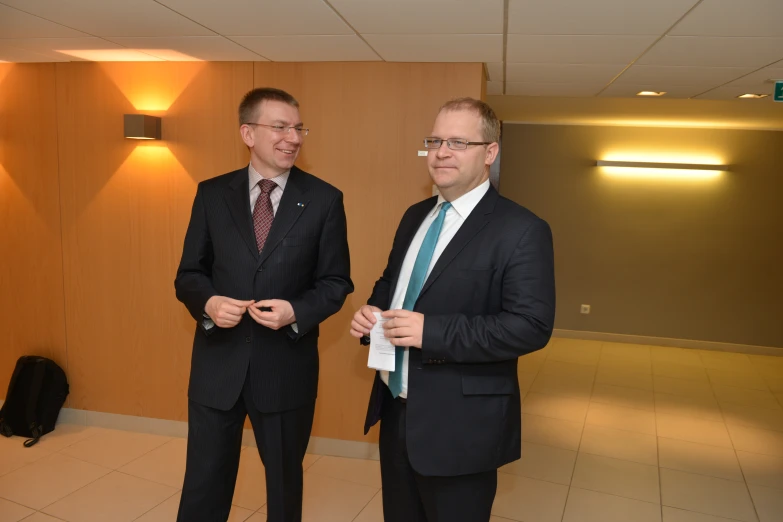 two men standing in a large room holding ties