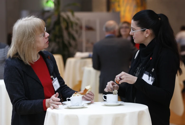 two women having tea and cake on a table in a fancy setting