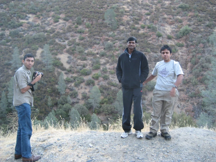 three men are standing on top of a hill