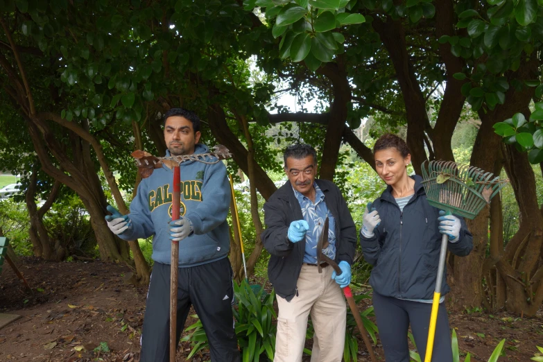 four people holding gardening tools posing for a po