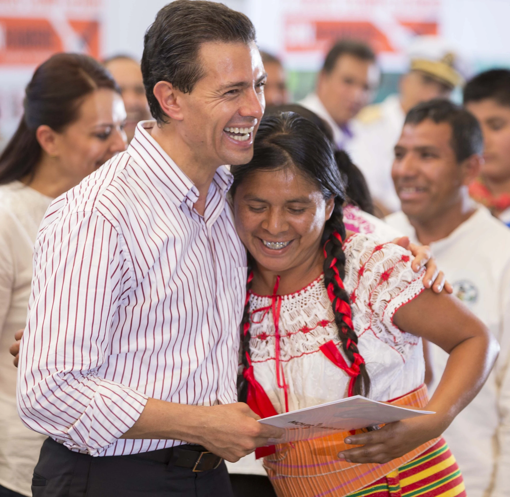 a man and woman smile at the camera as they have their arms around each other