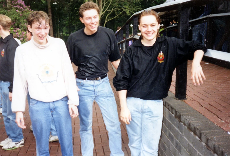 four men standing next to each other on a brick path