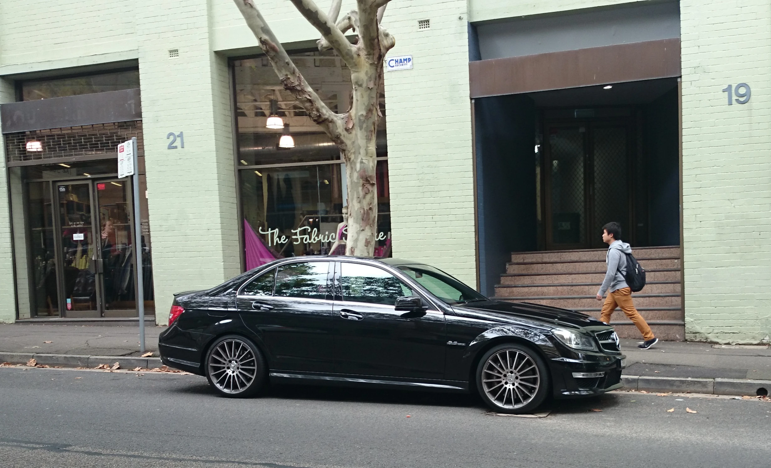 black car parked on the side of a road next to a tree