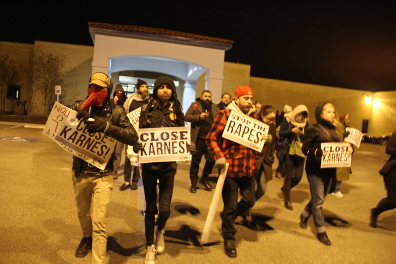 a group of people are holding signs while they walk down a street