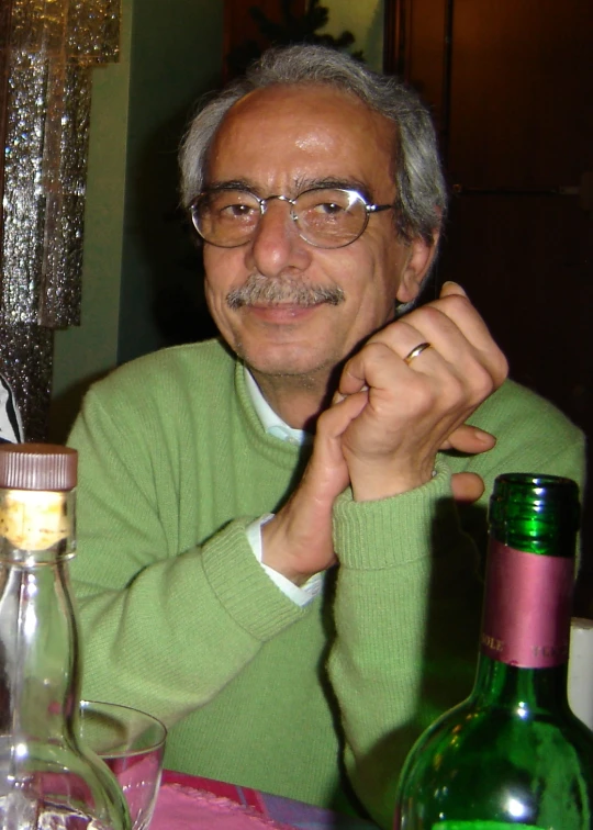 an older man poses with a bottle of alcohol in his hand