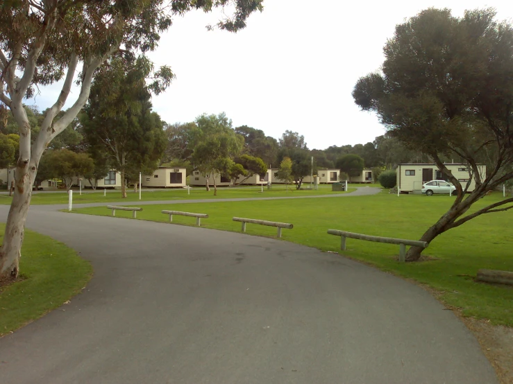 a paved path that has picnic benches on each side