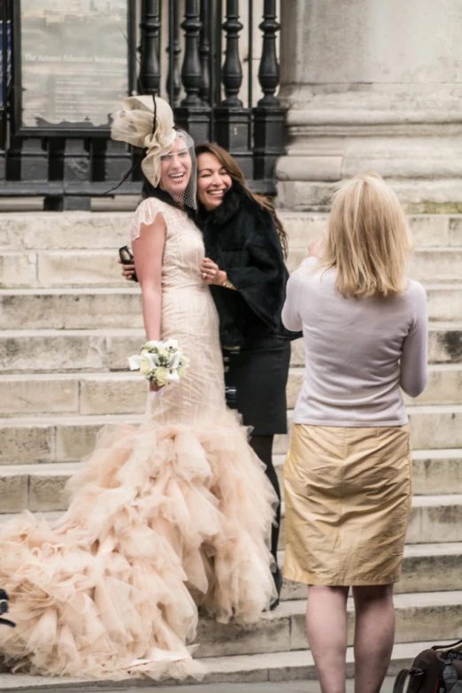 two women are hugging outside at the steps with two women in a gown