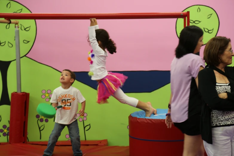 a  jumps up and swings around the pole in an indoor gym