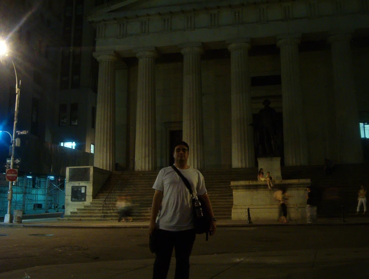 a man is standing in front of a very tall building at night