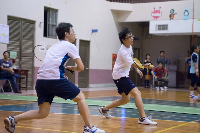 two young men running in a gymnasium during the day