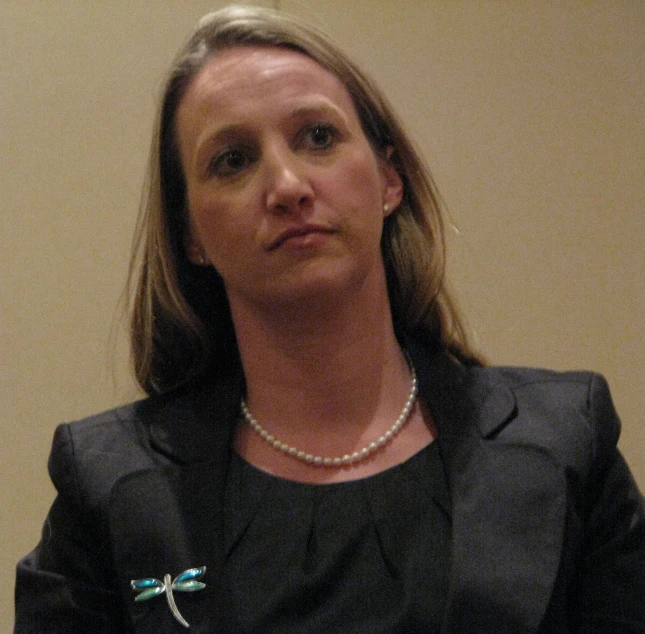 a woman wearing a pearl necklace and black blazer