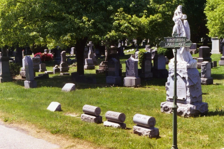 a cemetery in the summer with lots of cement benches and statues