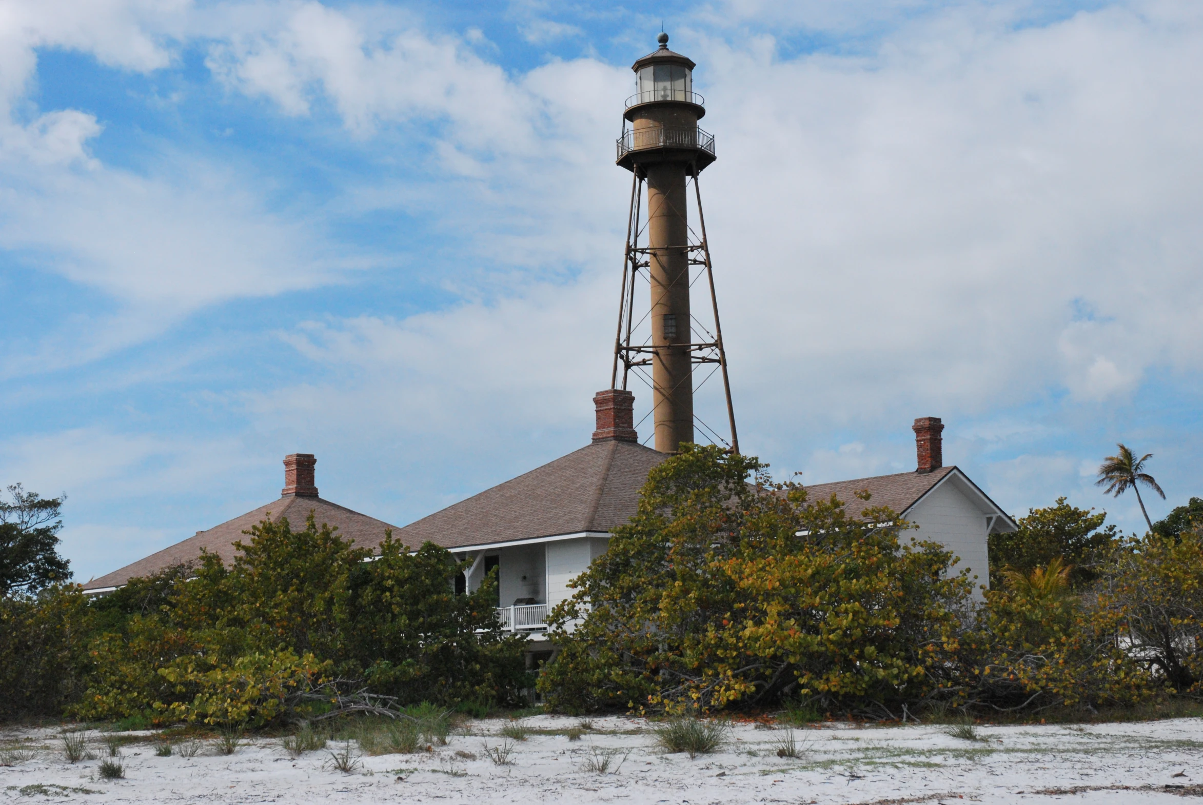 a house with a lighthouse in front of it on the beach