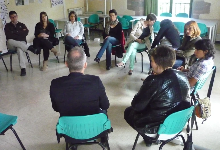a group of people sitting in chairs listening to each other