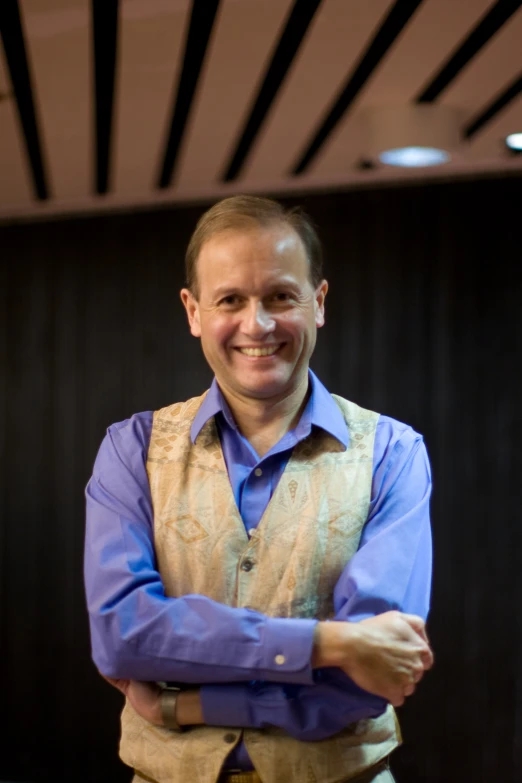 a man smiling and wearing a vest