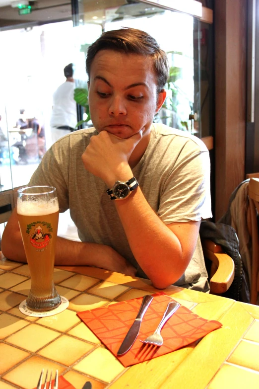 a man sitting at a table with a beer