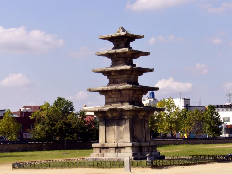 stone structure in middle of open grassy area near building