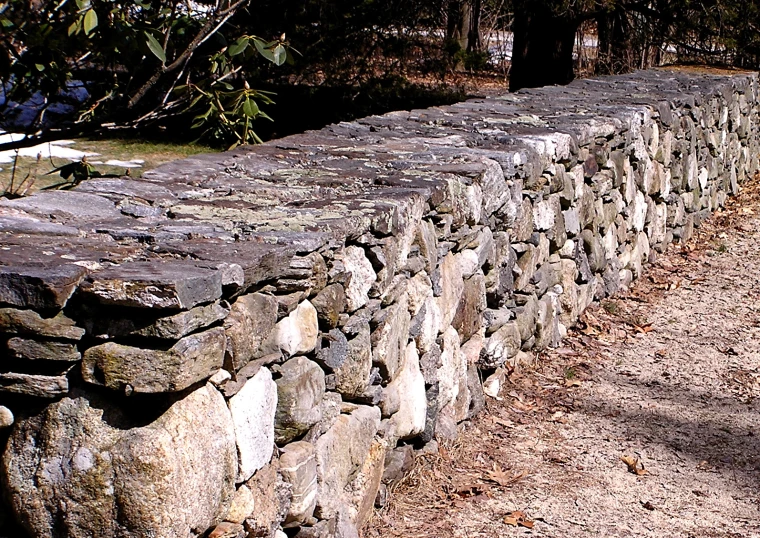 a stone fence with rocks laid up on top of it