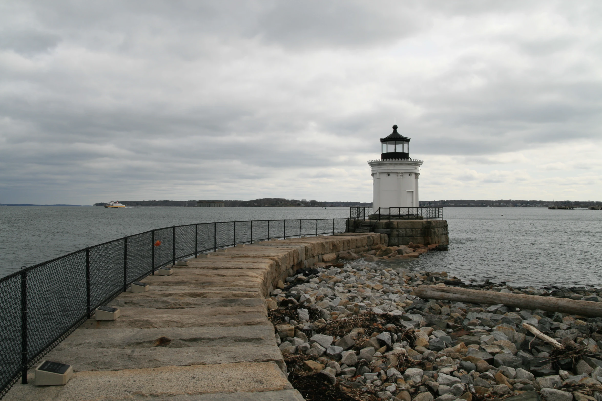 there is a white and black lighthouse next to the ocean