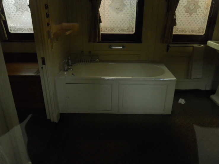 a white tub sitting inside of a bathroom next to two windows