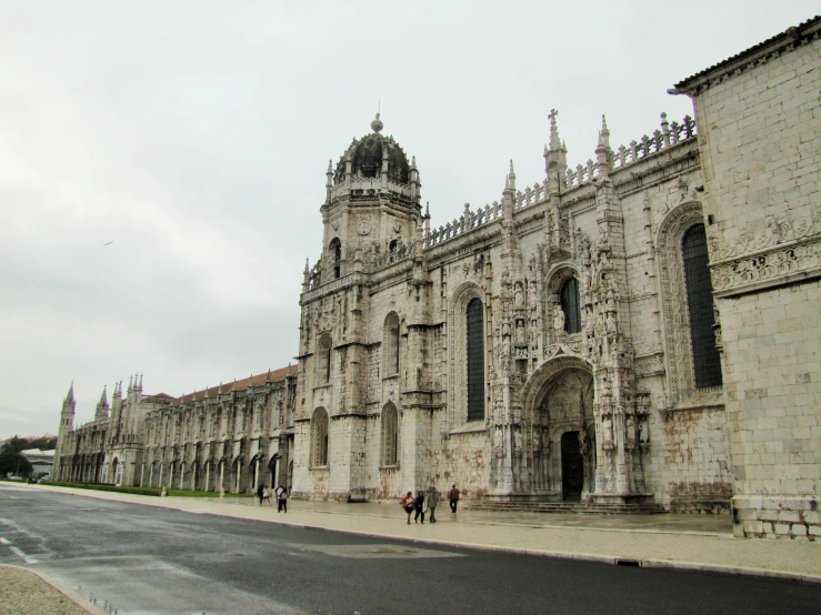 people walk past the architecture of an ancient cathedral