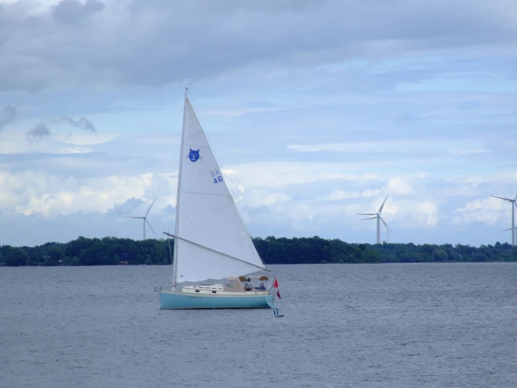 a sailboat sailing past wind turbines on the water