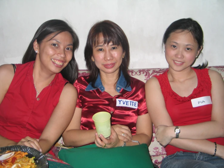 three asian women sitting down on a couch