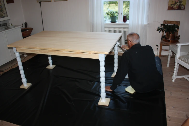 man on the phone sitting in the kitchen with a table