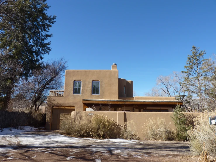 an adobe - style house with a clock on the front and corner of it