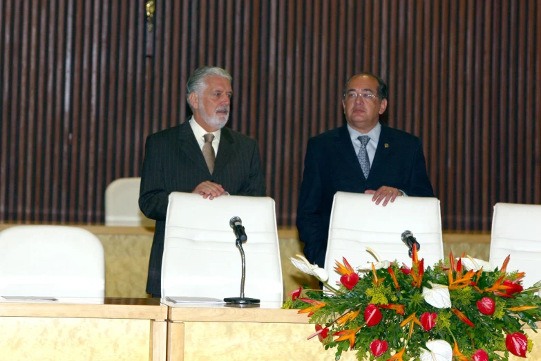 two men in suits stand by a podium and microphone