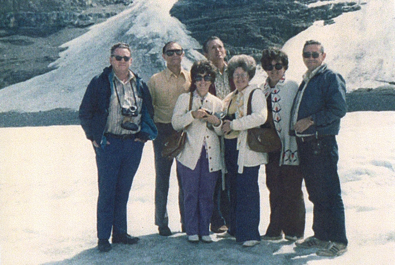 four friends pose for the camera in front of a mountain