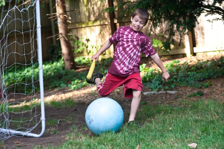 a young child standing in the yard with a baseball bat and ball