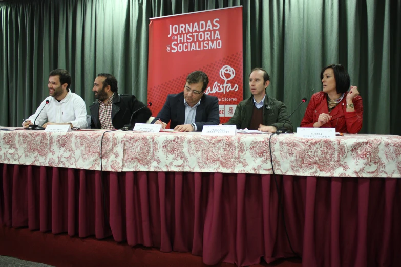 five people are sitting around a red table