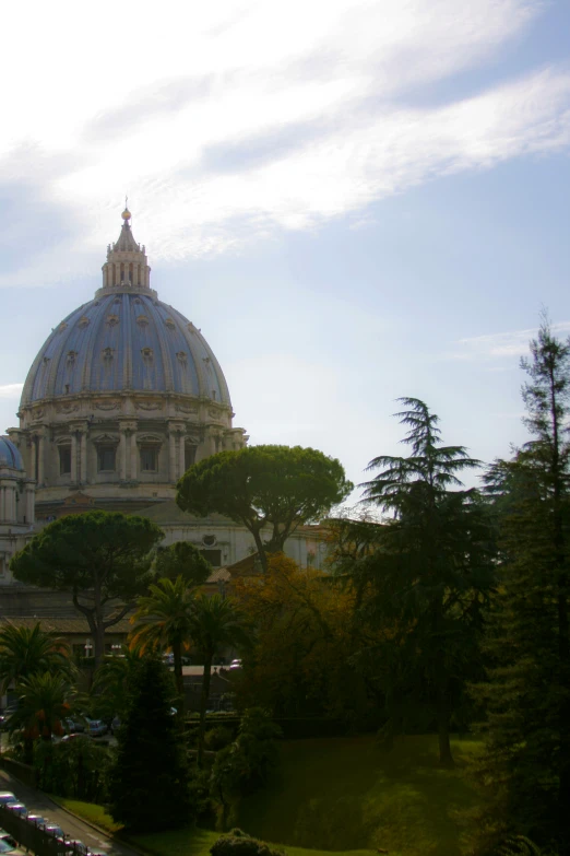 an old church with lots of trees on a hill in a city