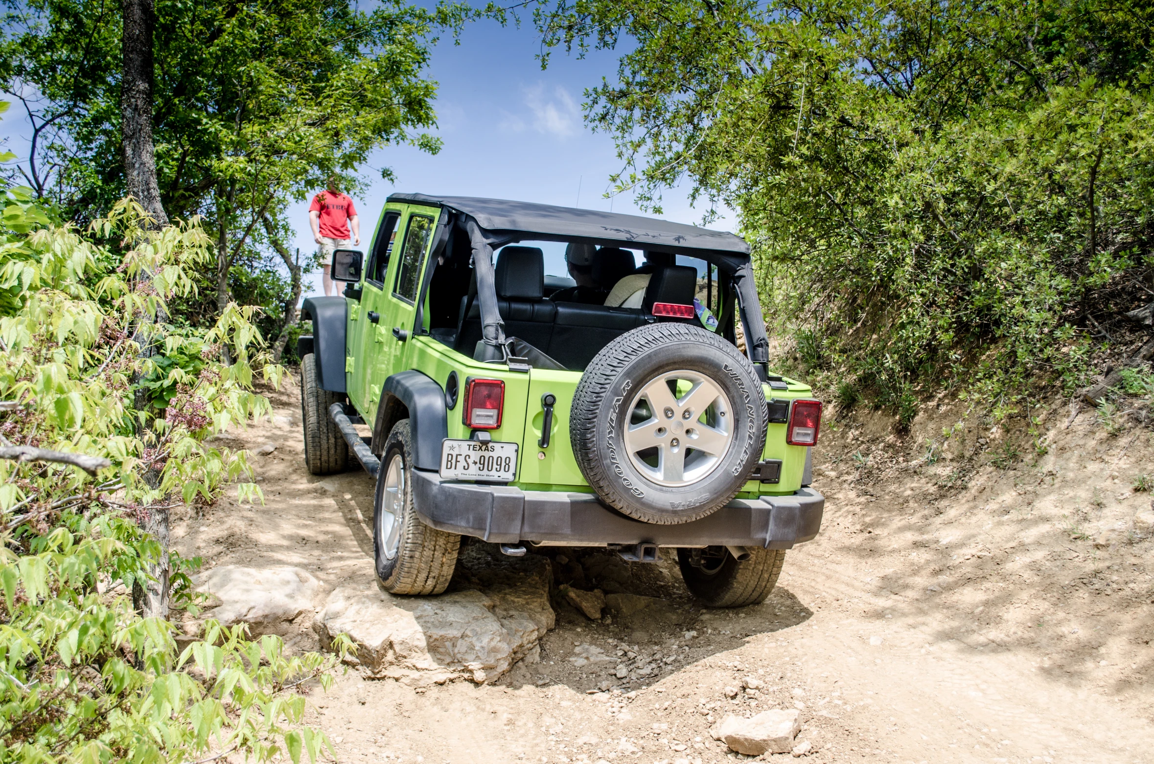 there is a green jeep thats driving up a hill