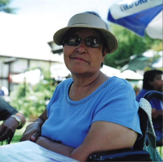 a woman sitting next to a woman with a hat and sunglasses on